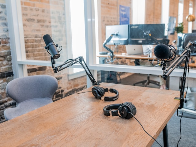 two black headphones on a brown wooden table for a podcast